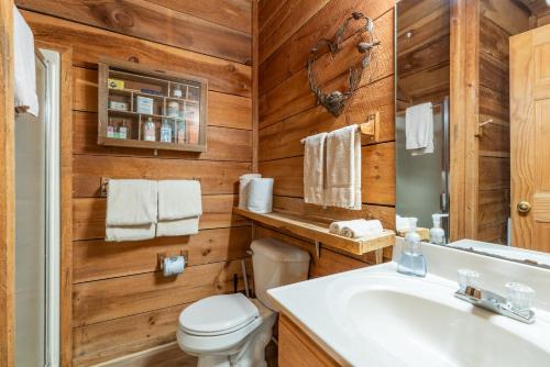 ein Badezimmer mit Holzwänden, einem WC und einem Waschbecken in der Unterkunft Heartwood in Sevierville