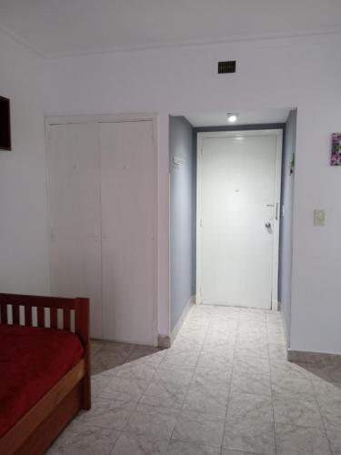 ein Schlafzimmer mit einer Tür und einem Bett und ein Zimmer mit weißen Wänden in der Unterkunft 1 Ambiente Zona Shopping Aldrey in Mar del Plata