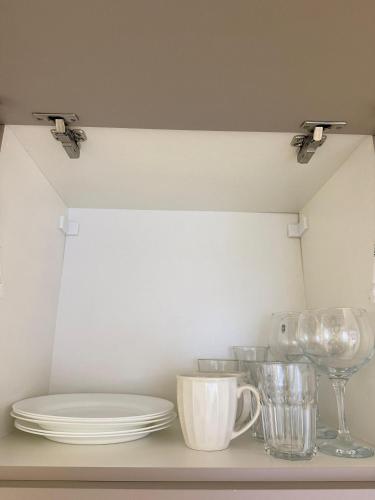a shelf with plates and cups and glasses on it at Studio Charmoso Próximo ao Parque do Lago - SPMA01 in Guarapuava