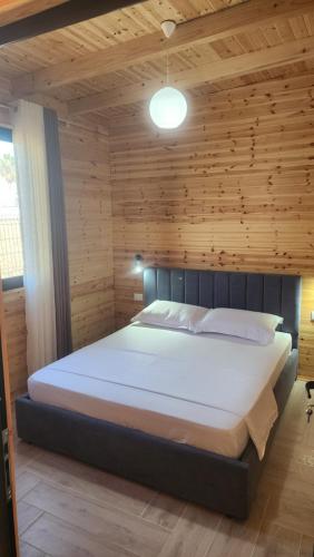a bedroom with a large bed with a wooden wall at UniKlajd Villa-s in Golem