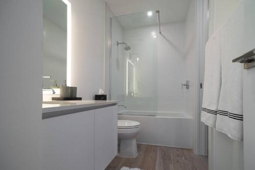 a white bathroom with a toilet and a shower at Sea Dreams 3-contemporary Condo Wpanoramic Views in West Bay