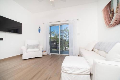 a white living room with a white couch and a window at Seamist 308 Views Of North Sound in West Bay