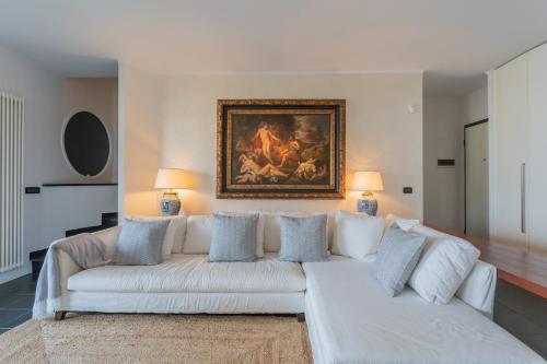 a white couch in a living room with a painting on the wall at Besana 9 on the Lake - Private garden & parking by Rent All Como in Moltrasio