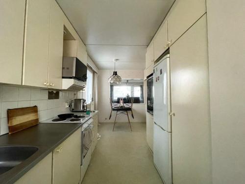 a kitchen with white cabinets and a white refrigerator at Ground floor 3 bedroom apartment, free parking in Oulu
