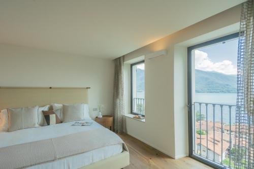 a bedroom with a bed and a large window at Villa Donatella with Private SPA & Infinity Pool by Rent All Como in Gravedona