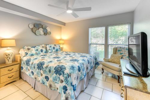 a bedroom with a bed and a flat screen tv at 4 Mi to Siesta Key Beach Condo with Pool Access in Sarasota