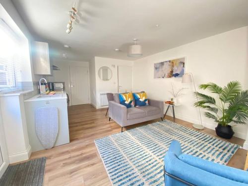 a living room with a blue couch and a table at Cozy One Bed Flat at Dawe Luxury Suites - An Entire Apartment near Ely Cathedral & Train Station - The Perfect Base to Explore Ely, Cambridge, Norfolk & London - 2 Guests Max & Pet Friendly in Ely