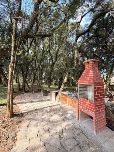 a brick fireplace in the middle of a park at Casa na Árvore em Guarapuava in Guarapuava