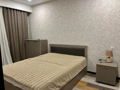a small bedroom with a bed and a lamp on a table at Gudauri apartment N209, Hotel Qumli in Kʼumlistsʼikhe