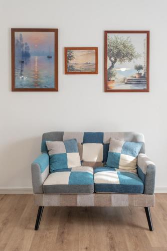 a couch in a living room with two pictures on the wall at Trilocale con piscina in Caprino Veronese