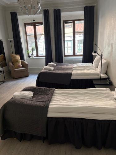 a bedroom with three beds and a chair and windows at Hotel Lemonade in Gothenburg