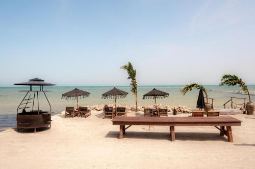 a beach with tables and chairs and umbrellas at AWA Holbox Hotel Boutique - Beach Front in Holbox Island