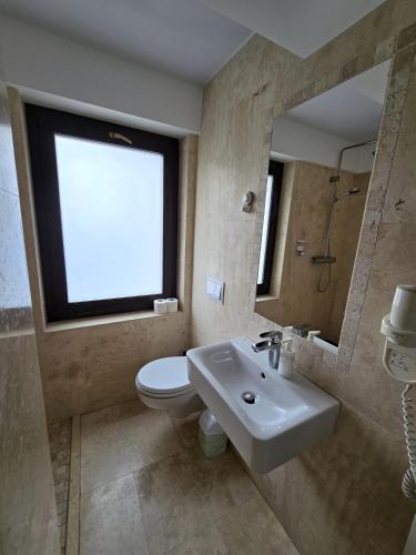 a bathroom with a sink and a toilet and a window at Dacia Residence Apartments in Bucharest