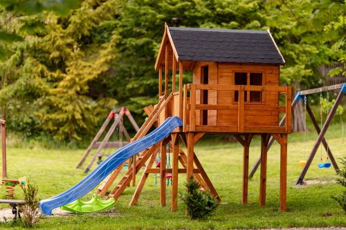 a wooden playground with a slide and a house at Domki Wierzchy in Wierzchy