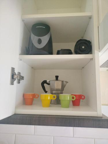 a cupboard with colourful cups and a coffee maker at Anaga y La laguna a tus pies in Santa Cruz de Tenerife