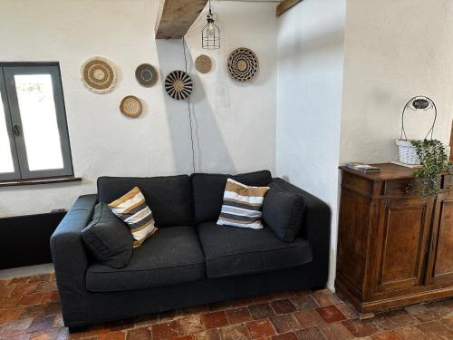 a living room with a black couch and a window at Charme ancien pigeonnier au cœur de la campagne in Ourouer-lès-Bourdelins