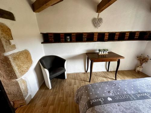 a bedroom with a table and a chair and a bed at Charme ancien pigeonnier au cœur de la campagne in Ourouer-lès-Bourdelins