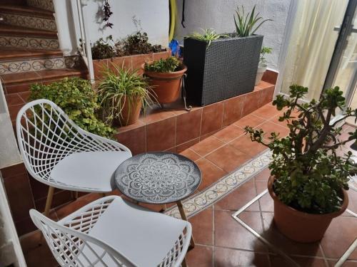 a balcony with white chairs and potted plants at La Casita de Paula in Mairena del Aljarafe