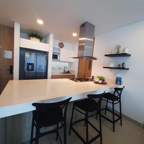a kitchen with a counter with four bar stools at Reserva Del Mar Apartamentos in Gaira