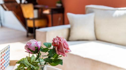 a vase with flowers on a table next to a couch at Spacieux T2 Place de la République in Dijon