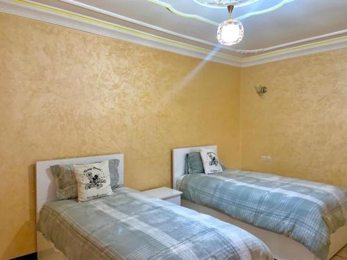 a bedroom with two beds and a chandelier at Grand Appartement Luxueux En Plein Taroudant in Taroudant