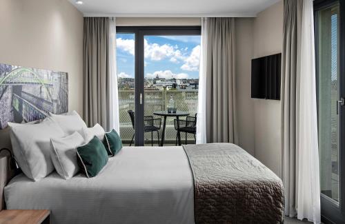 a bedroom with a bed and a balcony with a table at Leonardo Hotel Vienna City West in Vienna