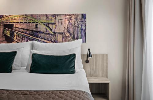 a bedroom with a bed with a painting on the wall at Leonardo Hotel Vienna City West in Vienna