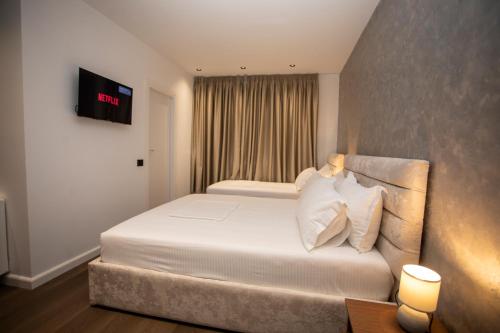 a bedroom with a bed and a tv on the wall at Villa Klaus Hotel in Tirana