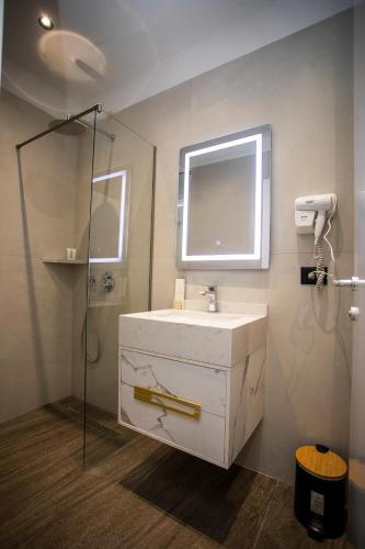 a bathroom with a white sink and a mirror at Villa Klaus Hotel in Tirana