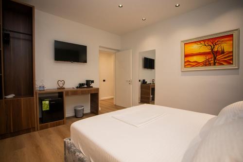 a bedroom with a bed and a flat screen tv at Villa Klaus Hotel in Tirana