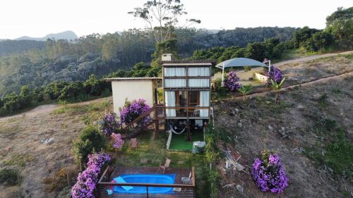 a small house on a hill with purple flowers at Chalé dos Manacás Duplex in Venda Nova do Imigrante