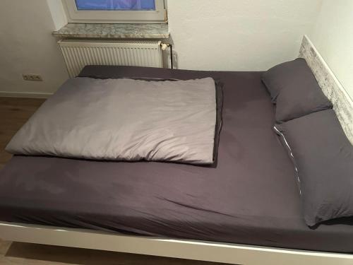 a bed with brown sheets and a white pillow on it at Hotelshausbückeburg in Bückeburg