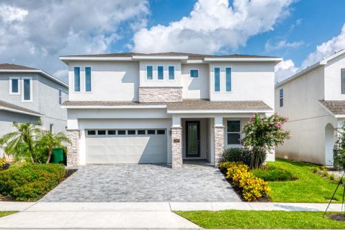 a white house with a garage at Magnificent Home Near Disney With Theater Room, Pool Table, Waterpark & Resort Access At Encore Resort Reunion - 7448Mr in Kissimmee