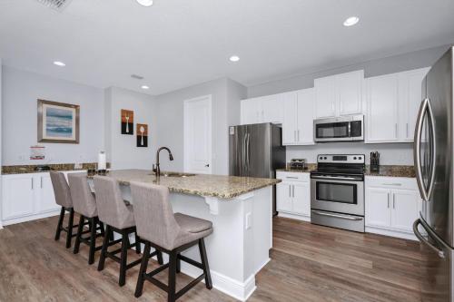 une cuisine avec des placards blancs et un îlot de cuisine avec des tabourets de bar dans l'établissement Grand Home Near Disney With Private Pool And Waterpark & Resort Access At Encore Resorts Reunion - 7519Mr, à Kissimmee