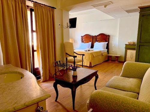 a hotel room with a bed and a couch and a table at Great Greece Le Convivial Suites in Xylokastron