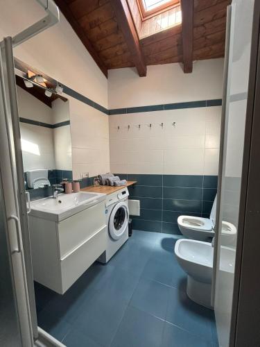 a bathroom with a toilet sink and a washing machine at Vallicella House in Fanano