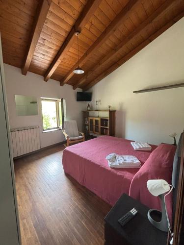 a bedroom with a red bed and a wooden ceiling at Vallicella House in Fanano