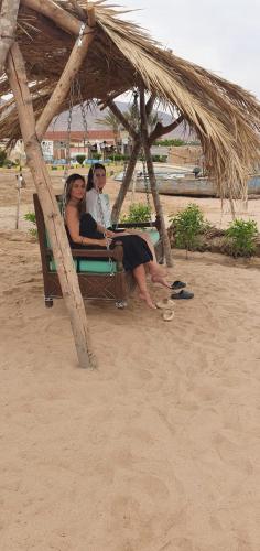 two people sitting on a swing on the beach at Panorama Lodge Nuweiba in Nuweiba