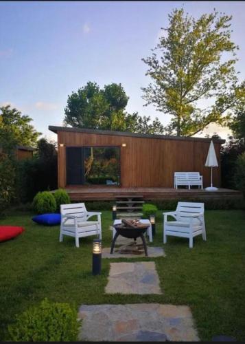 a backyard with three white chairs and a bench at Pamera Garden Hotel in Kılıçlı