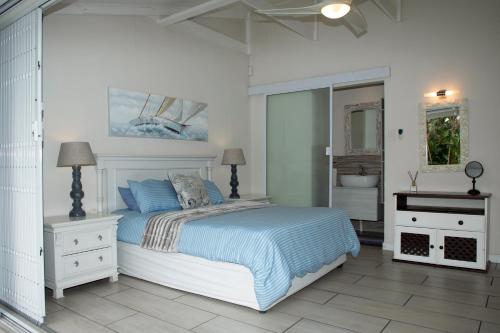 ein weißes Schlafzimmer mit einem Bett und einem Spiegel in der Unterkunft Sea Cottage in Port Shepstone