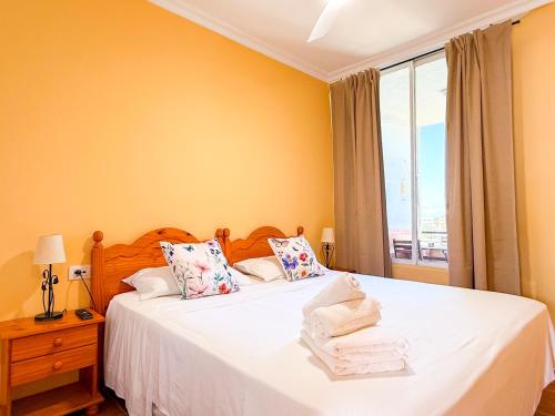 a bedroom with a bed with white sheets and a window at Piso los Agaves in Costa de Adeje