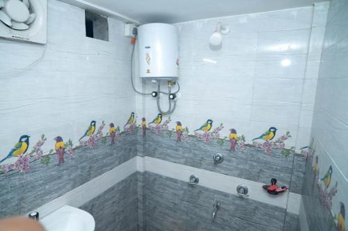a bathroom with a mural of birds on the wall at Binay chapa homestay in jaldapara in Mādāri Hāt