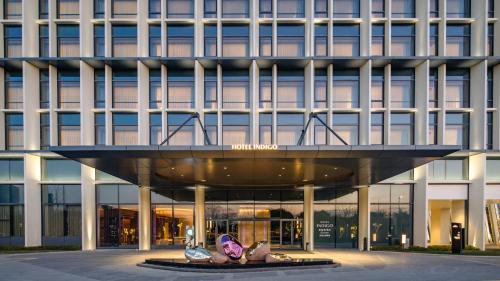 a building with two statues in front of it at Hotel Indigo Wuxi Taihu New City in Wuxi
