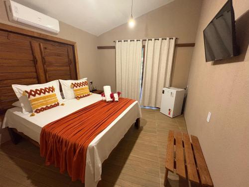 a bedroom with a bed with a television and a bench at Chalés Refúgio Fortim in Fortim