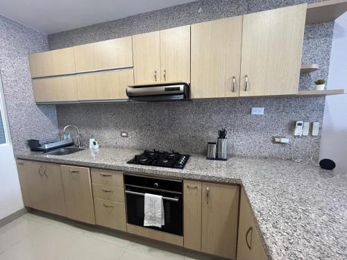 a kitchen with wooden cabinets and a stove top oven at Reserva Del Mar Apartamentos in Gaira
