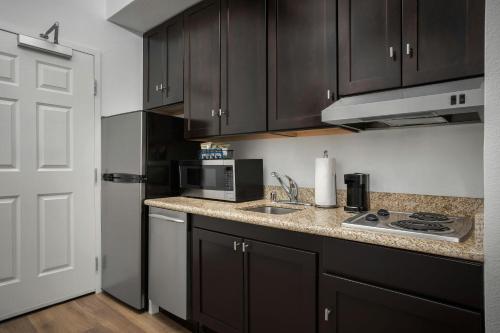 a kitchen with black cabinets and a sink and a microwave at TownePlace Suites El Centro in El Centro