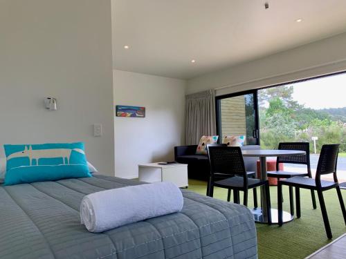 a bedroom with a bed and a table and chairs at Camp Waipu Cove in Waipu