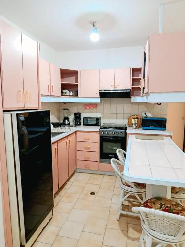 a kitchen with pink cabinets and a black refrigerator at Apartamento Punta Brava en el Centro de Tucacas in Tucacas
