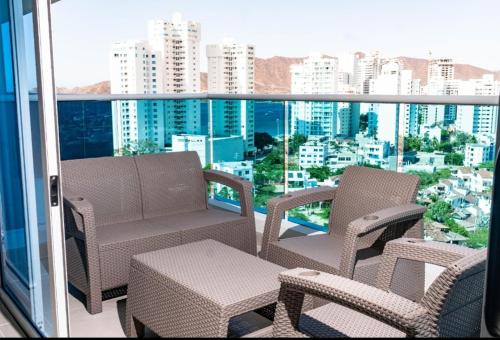 a balcony with chairs and tables and a view of a city at Reserva Del Mar Apartamentos in Gaira