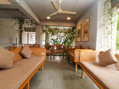 a restaurant with benches and tables and plants at Hotel Tattva Suites in Pune